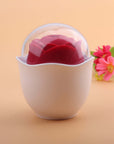 Red Nectar rose-shaped vibrator resting in a white cup-shaped holder beneath a clear dome cover
