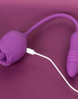 Purple Rhea rose tongue vibrator with a flexible connecting cord, rounded ribbed opposite end and white magnetic cable attached to the rose body