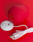 Red rose tapping stimulator showing two underside contacts beside its white round magnetic USB charging dock