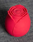 Angled Red rose tapping stimulator on grey fabric showing the concentric central pad, layered petals and single button
