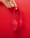 Rose tongue vibrator and connected egg photographed with the flexible cord in an inverted U shape, showing the two controls on the rose body