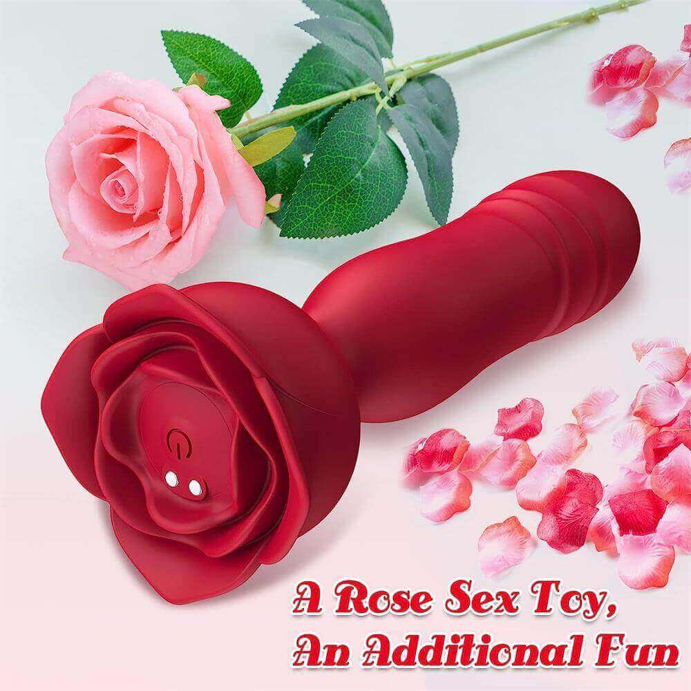 Red rose thrusting plug beside flower petals, showing its ribbed shaft, wide rose base, underside power button and two magnetic charging contacts