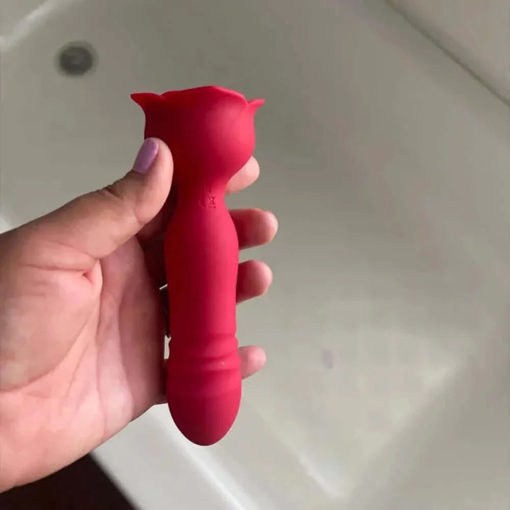 Hand holding the red rose thrusting plug to show its rounded tip, ribbed shaft, narrow neck and wider petal-shaped base