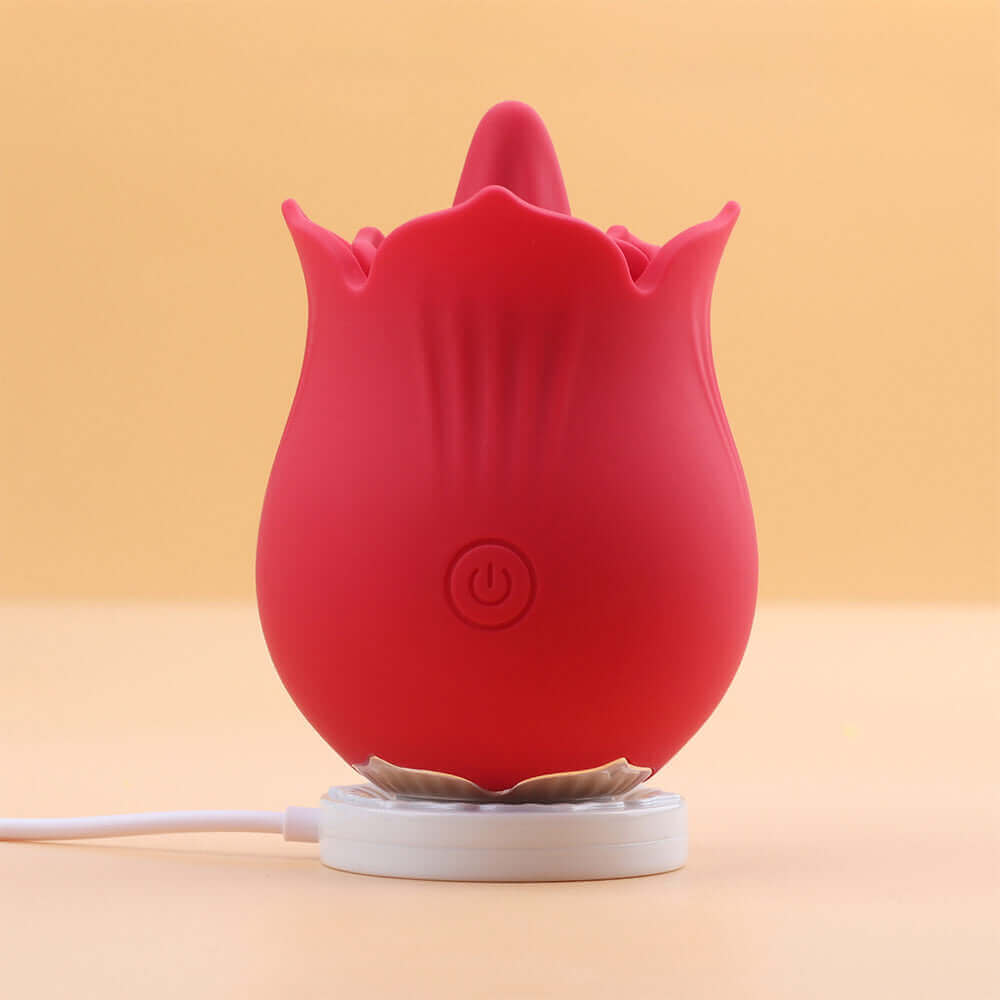 Red Doreen rose tongue vibrator standing on a white round magnetic charging base with a connected cable and its single front power button visible