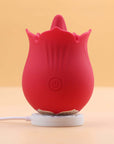 Red Doreen rose tongue vibrator standing on a white round magnetic charging base with a connected cable and its single front power button visible