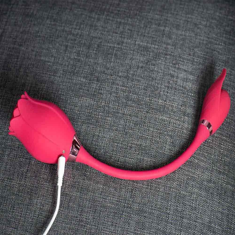 Rear view of the pink Mermaid rose suction vibrator with a white magnetic charging cable beside the metallic neck trim and the connected petal-shaped egg