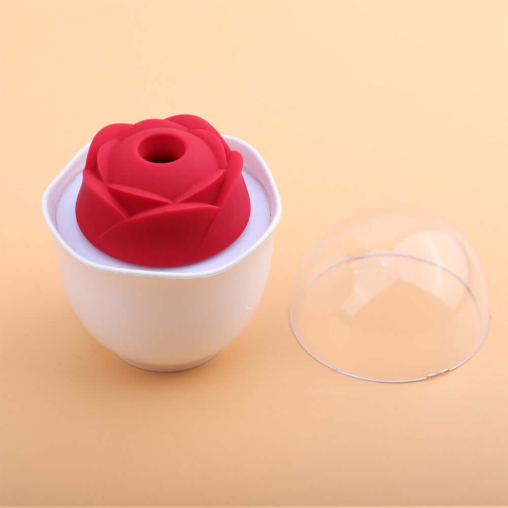 Red Nectar rose vibrator with a circular central opening in a white holder, with the clear dome cover removed and placed beside it