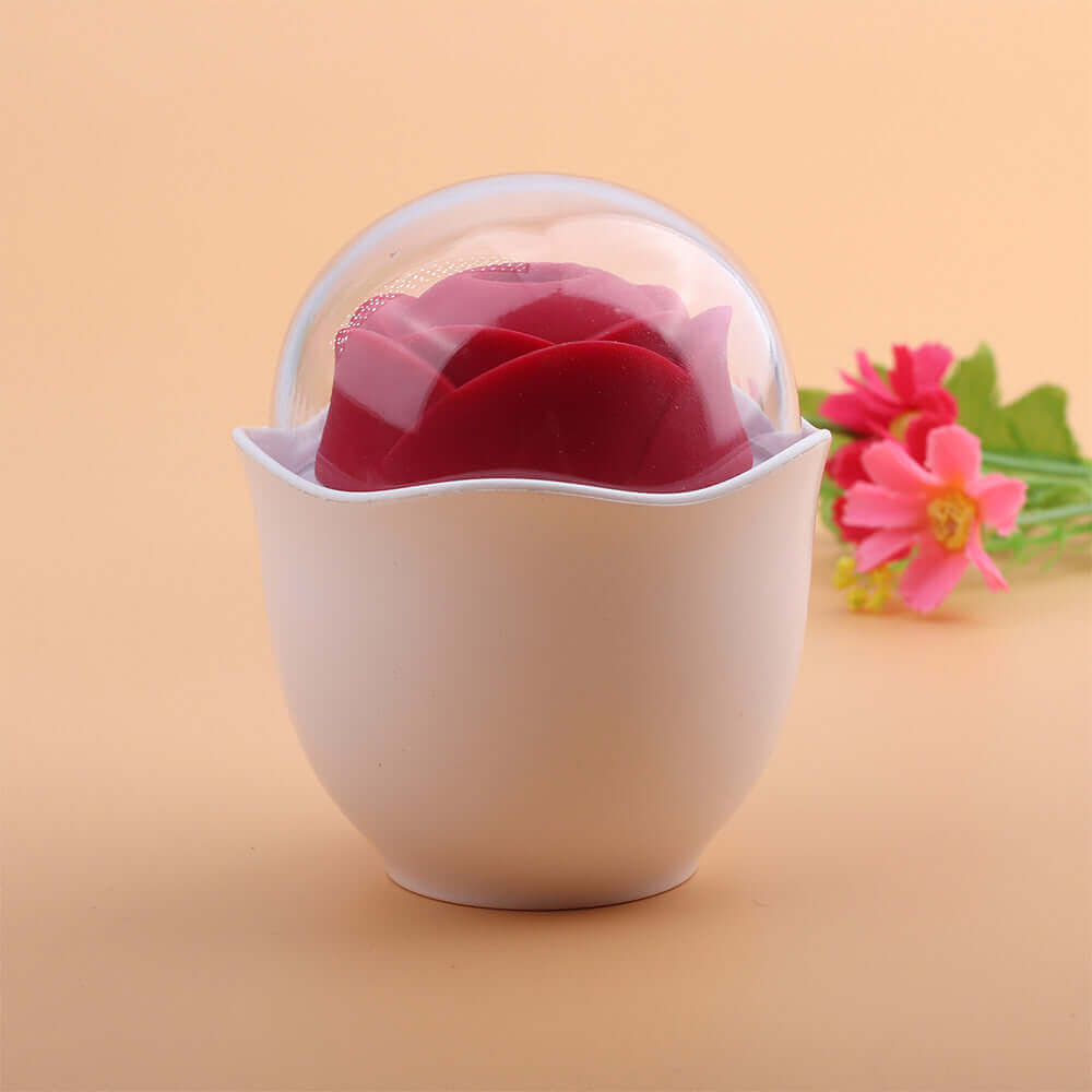 Red Nectar rose-shaped vibrator resting in a white cup-shaped holder beneath a clear dome cover