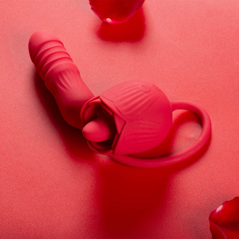 Red Rhea rose tongue vibrator with a raised tongue, curved ribbed opposite end and large loop handle arranged on a red surface