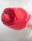 Close-up of the red Rhea rose head held in a hand under water, showing its rounded raised tongue and layered petals