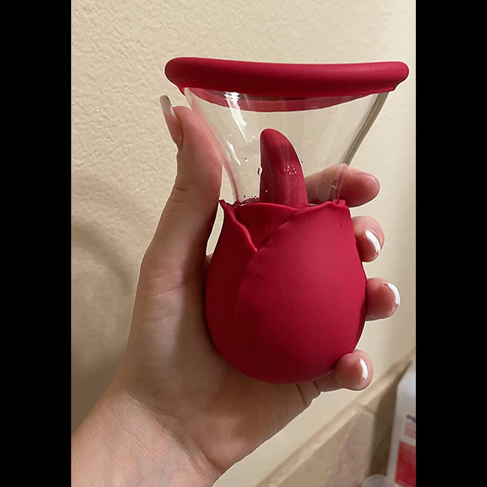 Hand holding the pink dual-action rose vibrator to show the scale of its rounded body, projecting tongue and clear flared cup