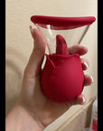 Hand holding the pink dual-action rose vibrator to show the scale of its rounded body, projecting tongue and clear flared cup