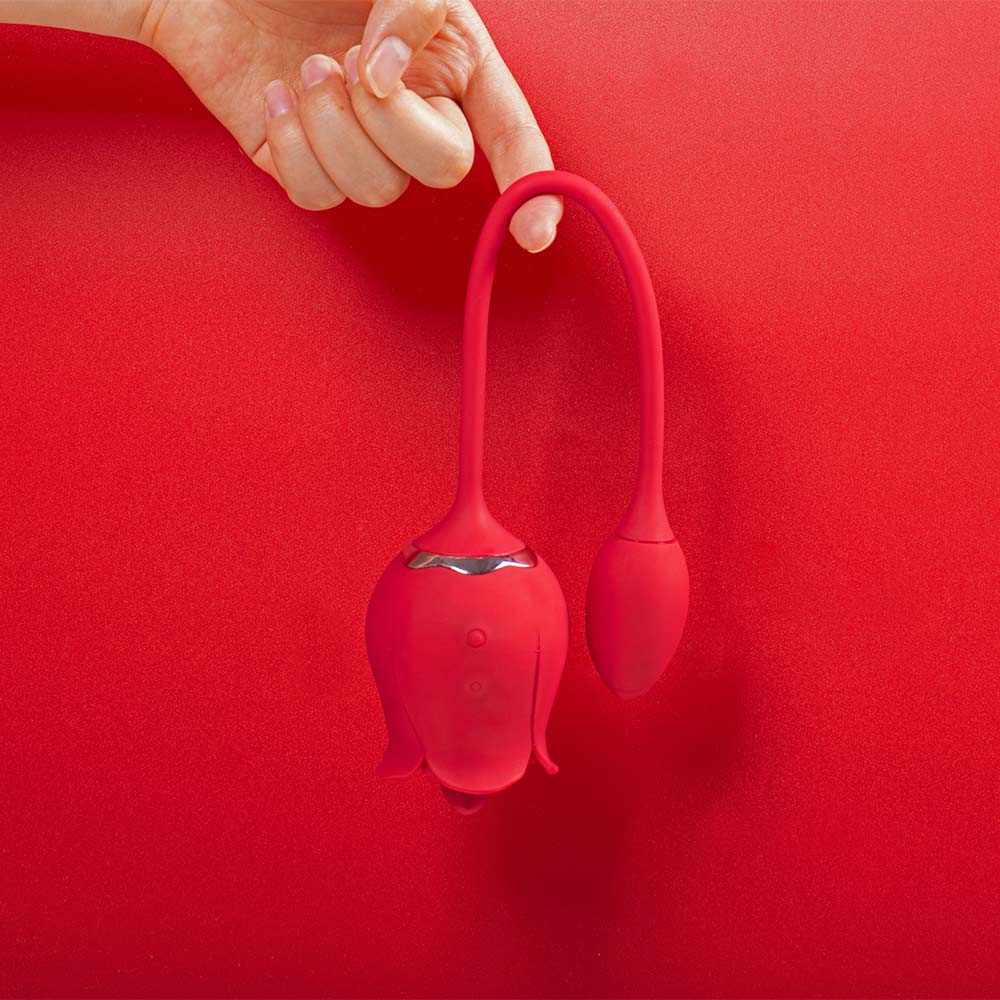 Rose tongue vibrator and connected egg photographed with the flexible cord in an inverted U shape, showing the two controls on the rose body