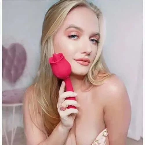 Person holding a red rose vibrator with a long opposite stem, providing handheld size context beside the flower head