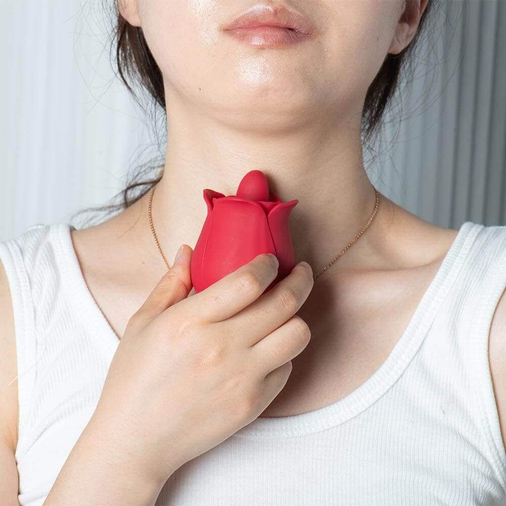 Person holding the red compact rose tongue vibrator near their collarbone, showing its handheld proportions and raised tongue