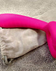 Side photograph of the Pink Y-1 vibrator showing its curved split head and textured long body resting on a fabric pouch
